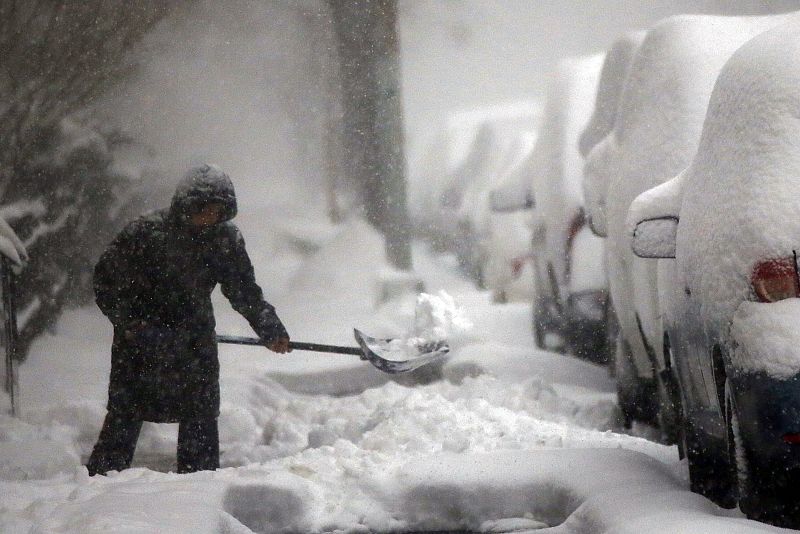 Una mujer retira la nieve de la calzada