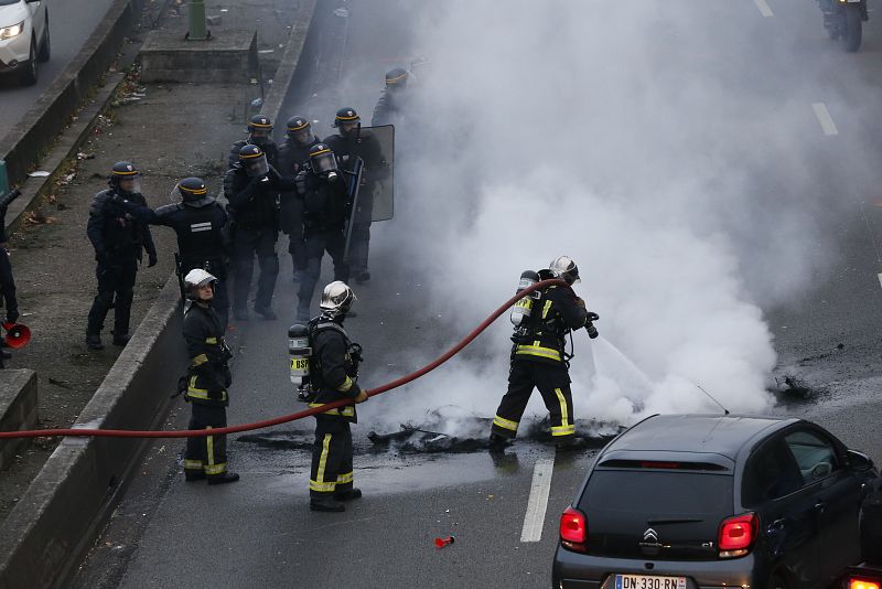 Un grupo de bomberos apaga una de las hogueras encendidas por los taxistas en la circunvalación de París
