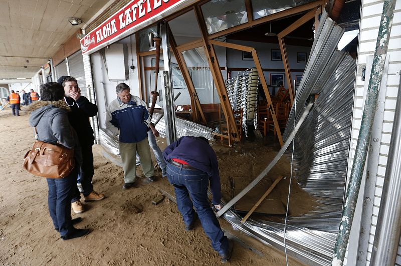 Trabajadores de la cafetería Aloha de Zarautz, observan el estado de sus instalaciones tras el azote de un fuerte temporal de mar.