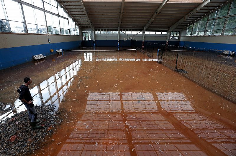 Un trabajador del Club de Tenis de San Sebastián observa el estado de varias canchas anegadas por el agua.