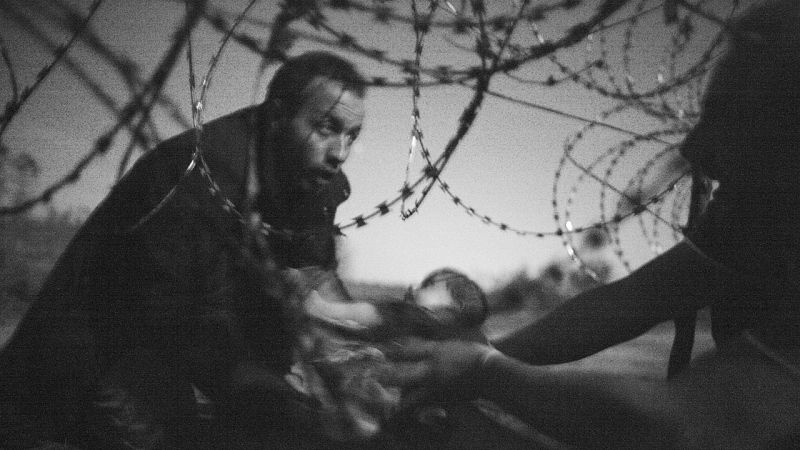Fotografía ganadora del World Press Photo 2016, firmada por el australiano Warren Richardson muestra a un refugiado pasando un bebe bajo las alambradas en la fontera serbo-húngara