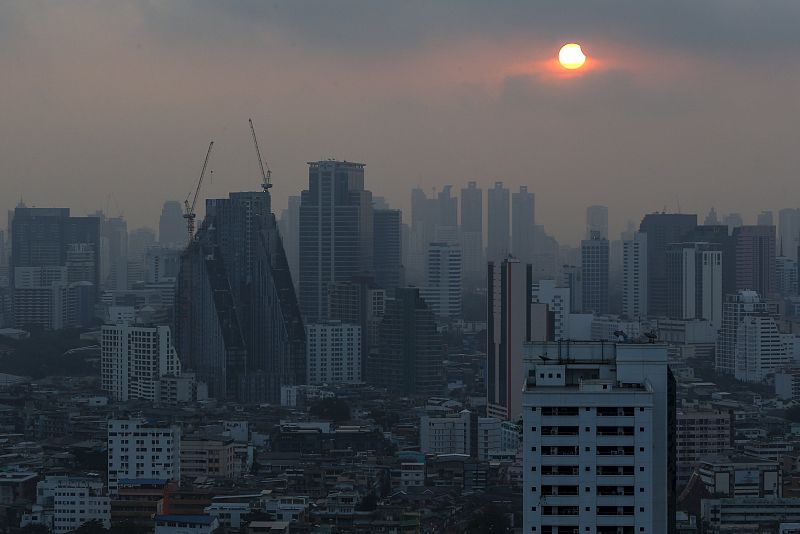 El Sol parcialmente eclipsado, sobre los edificios de la capital tailandesa, Bangkok.