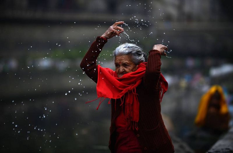 Un creyente nepalí de religión hindú reza y realiza abluciones en el río Bagmati, durante el eclipse, en Pashupatinath, Katmandú.
