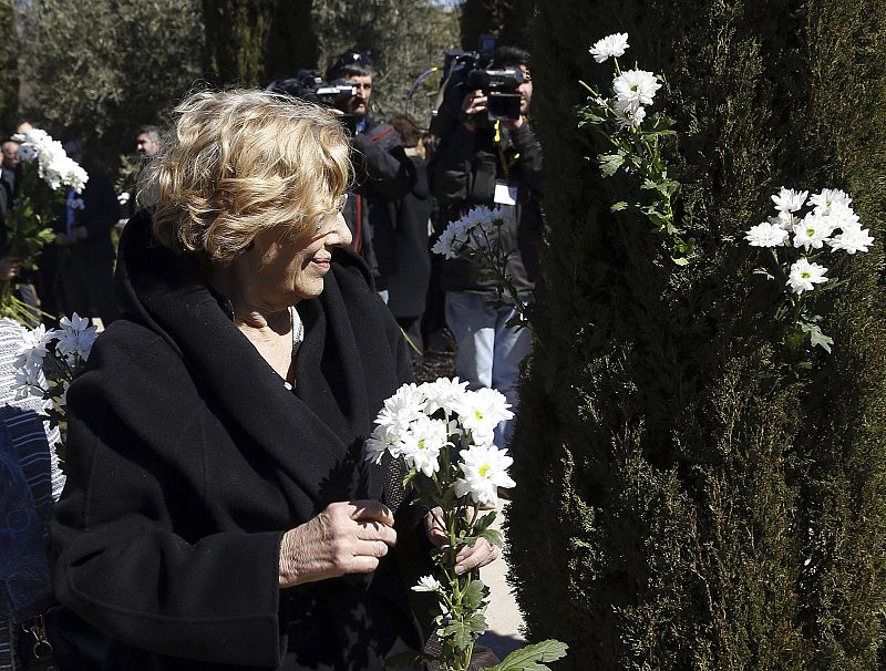 La alcaldesa de Madrid Manuela Carmena deposita unas margaritas durante el homenaje celebrada en el Bosque del Recuerdo del parque del Retiro