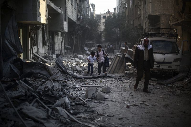 Dos niños caminan entre los escombros tras un bombardeo de las fuerzas sirias leales al presidente Bachar al Asad en Duma, un barrio rebelde de Damasco, en octubre de 2015.