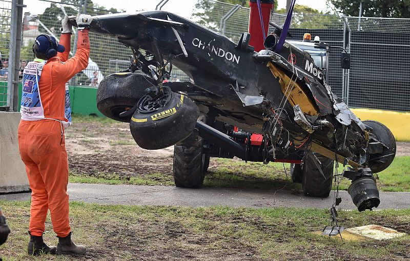 Los oficiales de la carrera revisan el estado del McLaren tras el accidente.