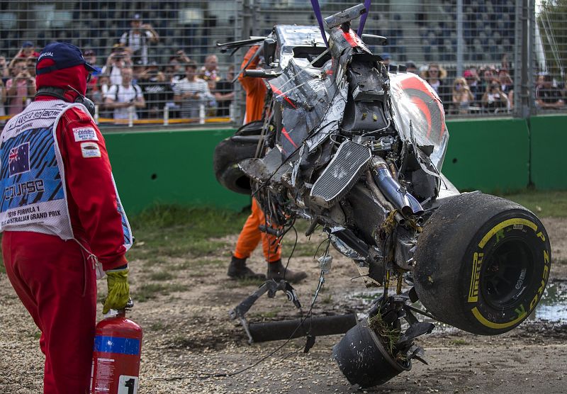 El coche de Alonso, convertido en un amasijo de hierros, es retirado por una grúa.