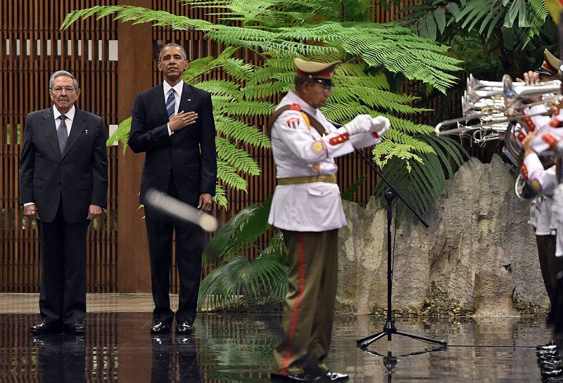Castro y Obama, firmes junto a la banda militar que interpreta los himnos nacionales respectivos.