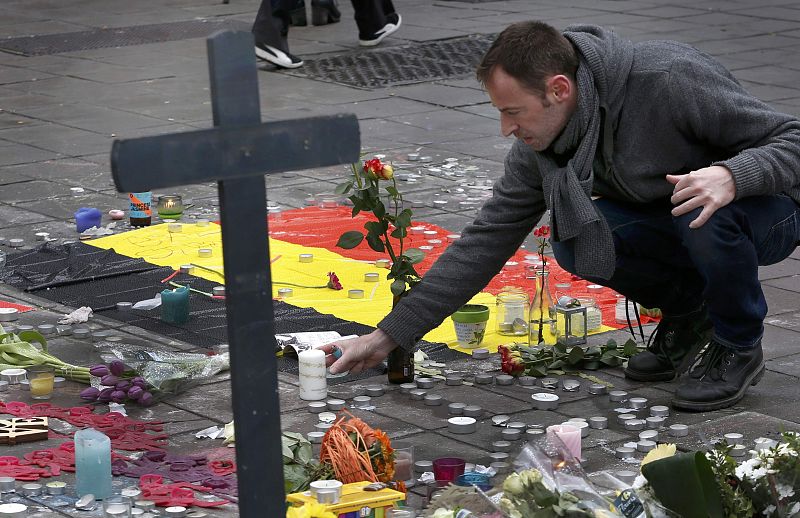 Un hombre coloca flores en una memorial improvisado de una calle de Bruselas.