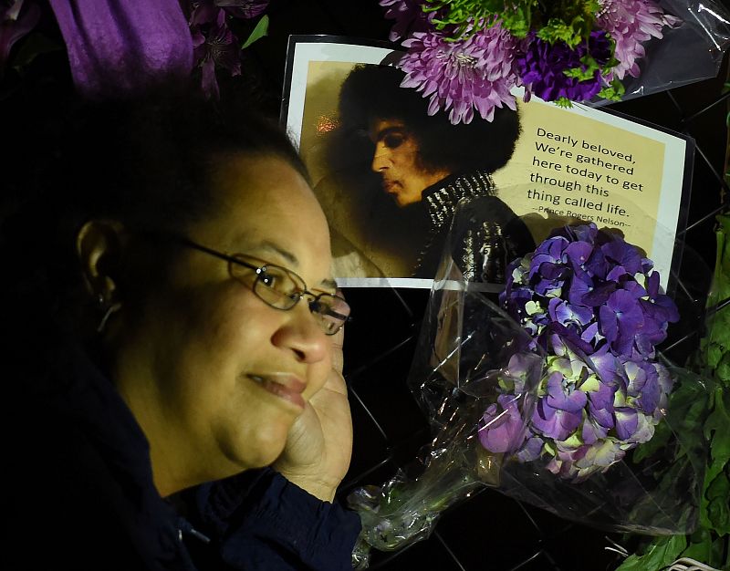 Una fan de Prince junto a mensajes y flores para recordar al atista en Paisley Park