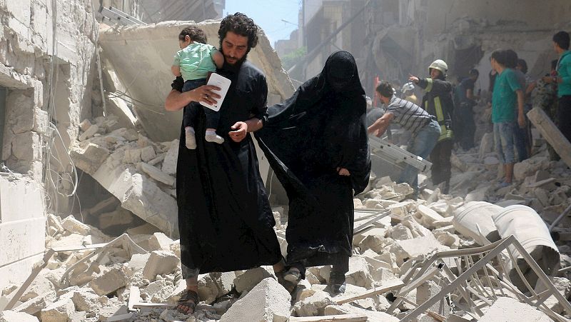 Una familia camina entre las ruinas de un edificio destruido en el barrio de Kalasa. AFP PHOTO / AMEER ALHALBI