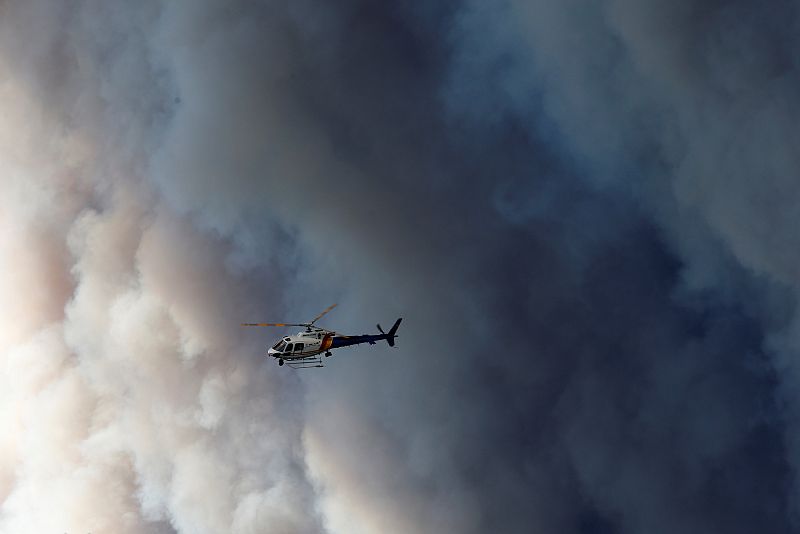 Un helicóptero sobrevuela Fort McMurray cerca de la gran humareda