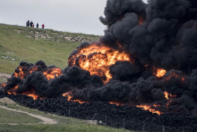Varias personas observan las llamas y la gran humareda en el cementerio de neumáticos