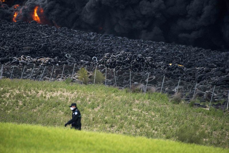 Un policía se protege con una máscara cerca del fuego