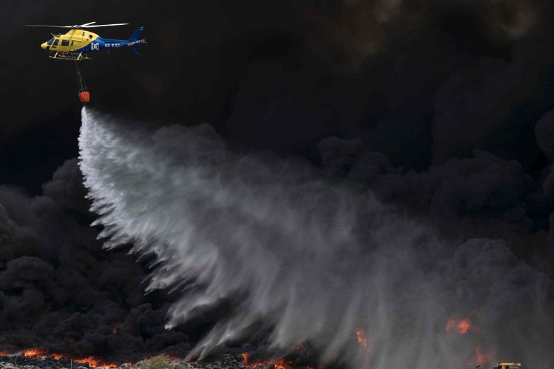 Un helicóptero de emergencias echa agua sobre los neumáticos ardiendo en Seseña (Toledo).