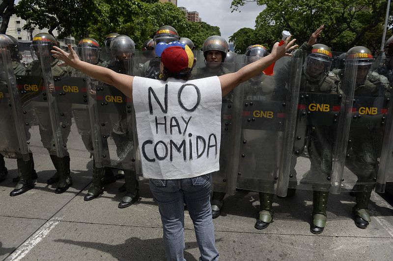 Una mujer que porta una pancarta en la que se lee "No hay comida" se manifiesta en Caracas