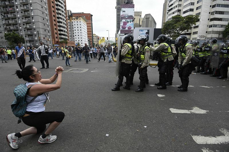 Una mujer se arrodilla delante de la Policía