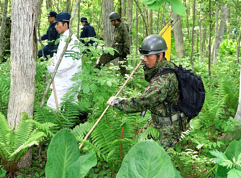 Japanese Self-Defense Force soldiers and police officers search for a 7-year-old boy who went missing on May 28, 2016 after being left behind by his parents, in Nanae town on the northernmost Japanese main island of Hokkaido