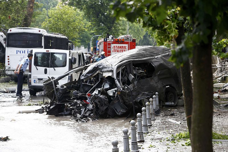 A destroyed van is pictured near a Turkish police bus which was targeted in a bomb attack in a central Istanbul district