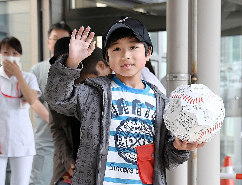 Yamato Tanooka, who was found by authorities in the woods nearly a week after his parents abandoned him for disciplinary reasons, waves as he leaves a hospital in Hakodate