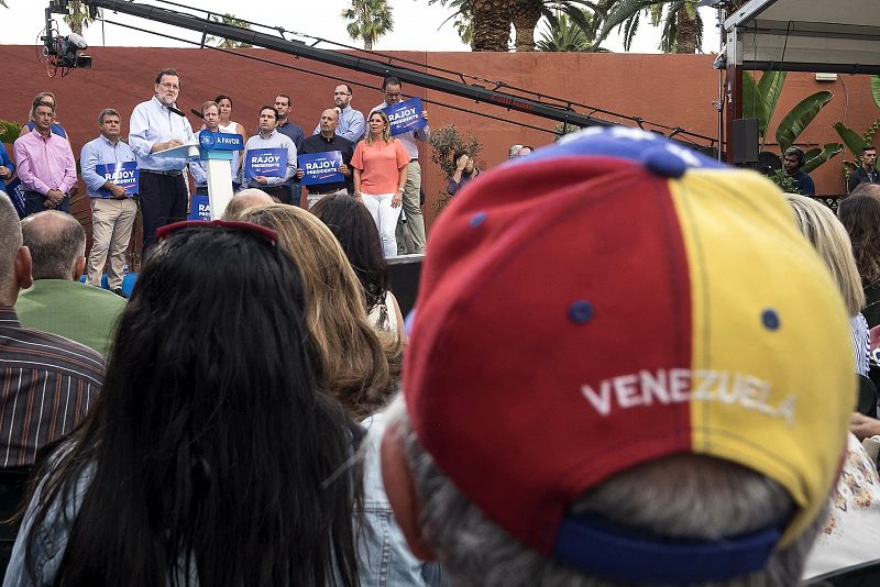 Un simpatizante del PP con una gorra de Venezuela, tema recurrente en la campaña electoral, escucha atentamente al candidato del PP a la reelección como presidente del Gobierno, Mariano Rajoy.