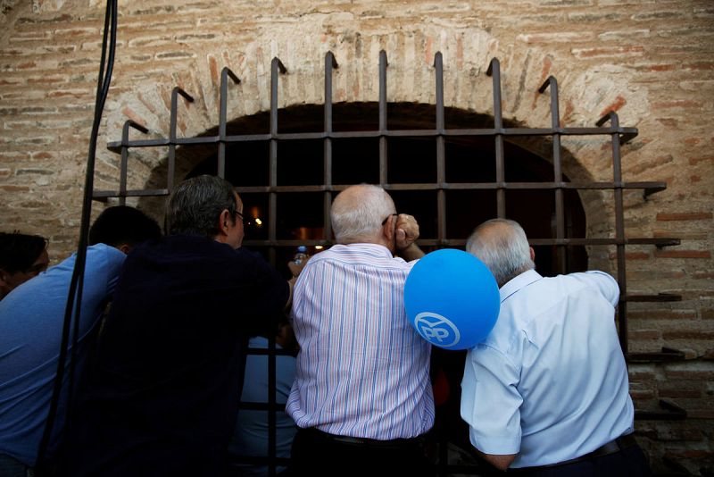 Simpatizantes 'populares' siguen desde una ventana la intervención en campaña de Mariano Rajoy en Torrijos (Toledo).