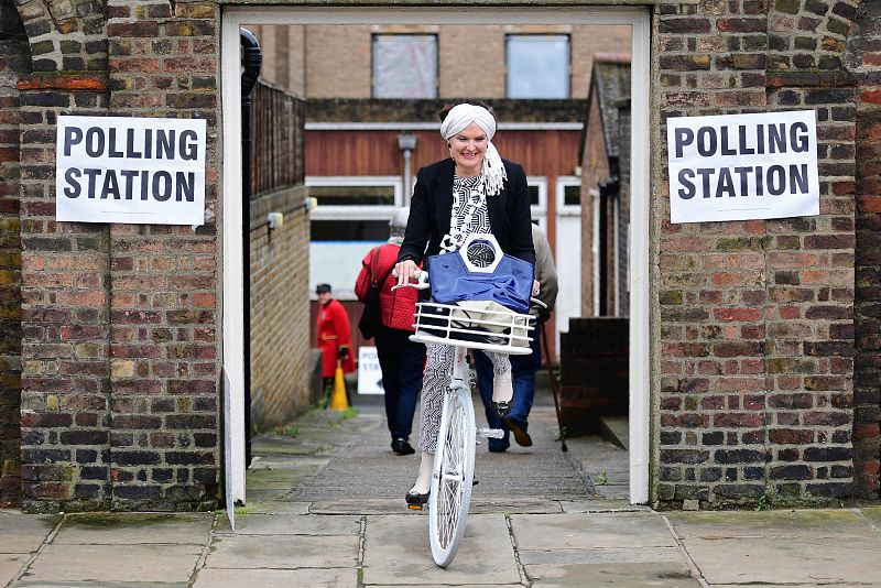 Una mujer conduciendo una bicicleta abandona un cebtro electoral en Chelsea, Londres