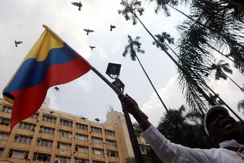 Un hombre ondea una bandera colombiana mientras asiste a la ceremonia "Adiós a la guerra" en la ciudad de Cali, Colombia.EL PAÍS