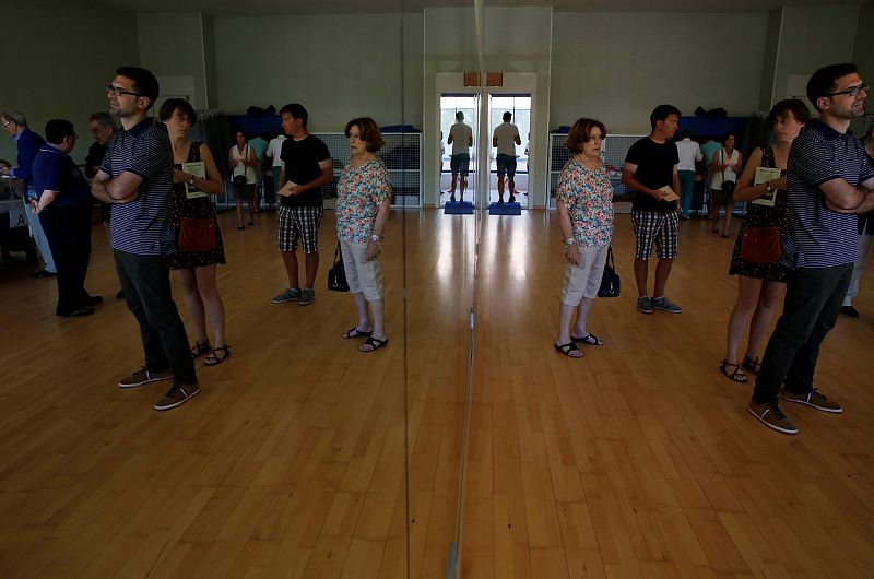 Varias personas esperan para depositar su voto en un colegio electoral en el municipio madrileño de Pozuelo de Alarcón