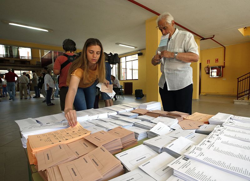 Votantes cogen sus papeletas en el colegio electoral Bernadette de Aravaca, en Madrid