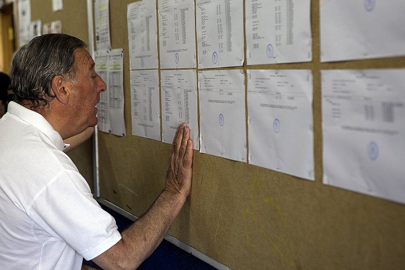 Un hombre consulta las listas electorales antes de votar en un colegio del madrileño barrio de Hortaleza