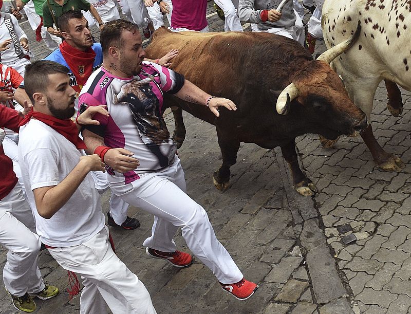 El último de los toros, de capa castaña, entra en el callejón en el sexto encierro de San Fermín 2016