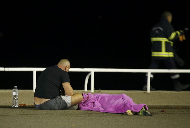 Un hombre sentado en el suelo junto a un cuerpo en el Paseo de los Ingleses en Niza