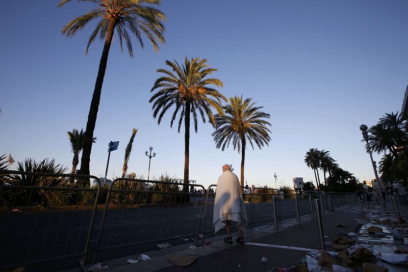 A man walks through debris on the street the day after a truck ran into a crowd at high speed killing scores celebrating the Bastille Day July 14 national holiday on the Promenade des Anglais in Nice