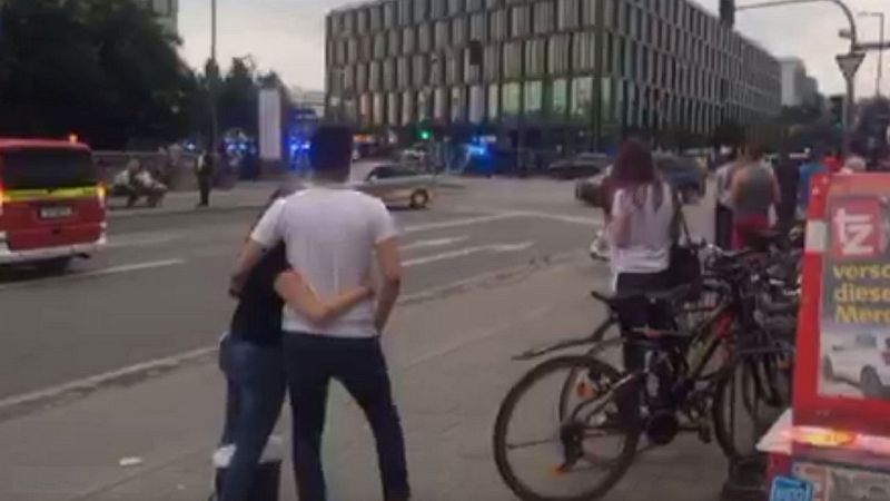 Varias personas observan el amplio despliegue policial en el centro comercial de Olympia, en Múnich, donde se ha registrado un tiroteo.