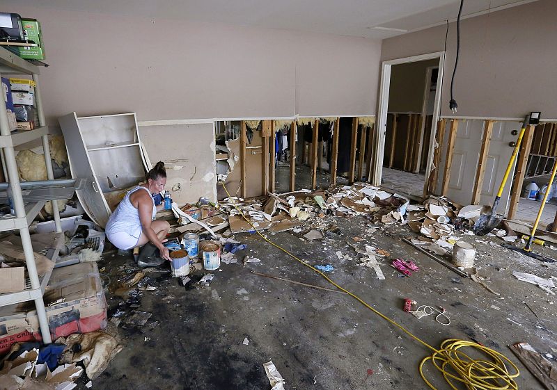 Sheryl Howard intenta salvar unas pocas latas de pintura en el garaje de su casa en Denham Springs.