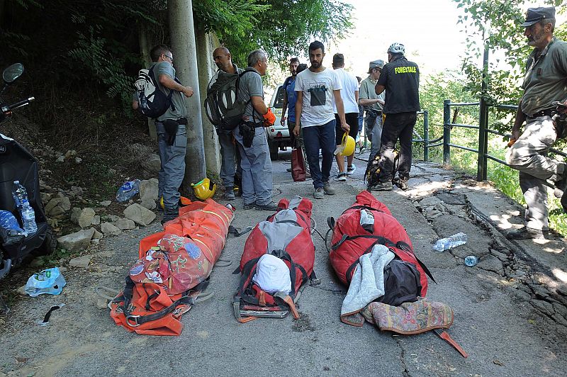 Miembros de los equipos de rescate junto a los cuerpos de tres víctimas del terremoto en Pescara del Tronto