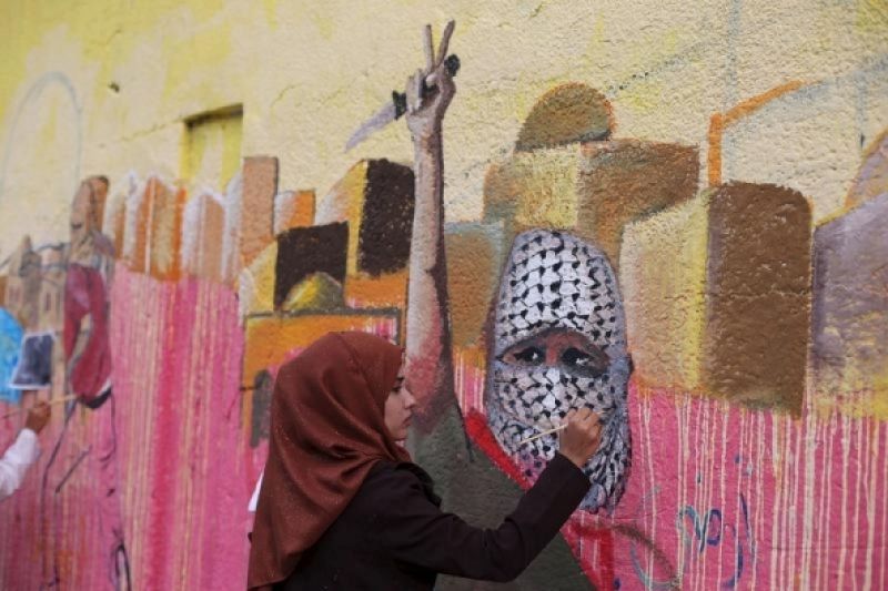 Una chica palestina pinta un mural en Rafah (franja de Gaza). Israel acusa a los dirigentes palestinos y a las redes sociales de incitar a la violencia.