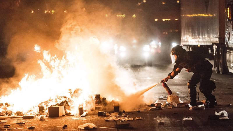 Un policía intenta extinguir un incendio en una carretera durante las protestas. El gobernador del estado de Carolina del Norte ha declarado el estado de emergencia y ha llamado a la Guardia Nacional.