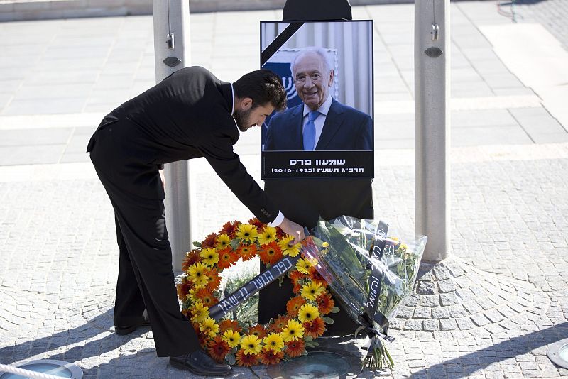 Un israelí coloca flores ante un retrato del expresidente israelí Simon Peres