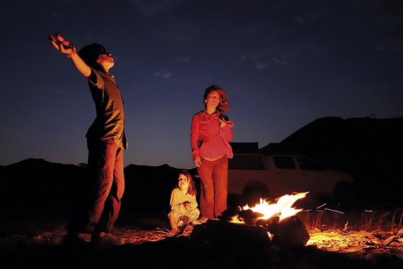 Unai, Amaia y Meritxell, junto a una hoguera en el desierto de Namibia.