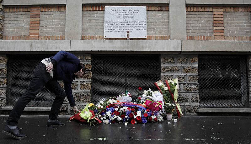 Un hombre deposita flores junto a la placa conmemorativa por las víctimas del atentado en 'La Belle Equipe'