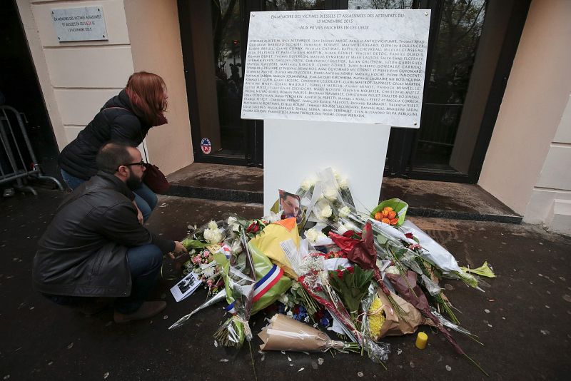 Dos personas depositan flores junto a la placa conmemorativa con los nombres de las víctimas en la sala Bataclan