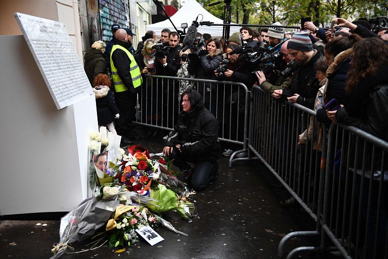 Una mujer deposita flores junto a la placa con los nombres de las víctimas en la sala Bataclan