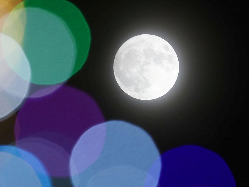 El resplandor de la luna se confunde con el de las bombillas de un árbol navideño en Sapporo, en el norte de Japón.