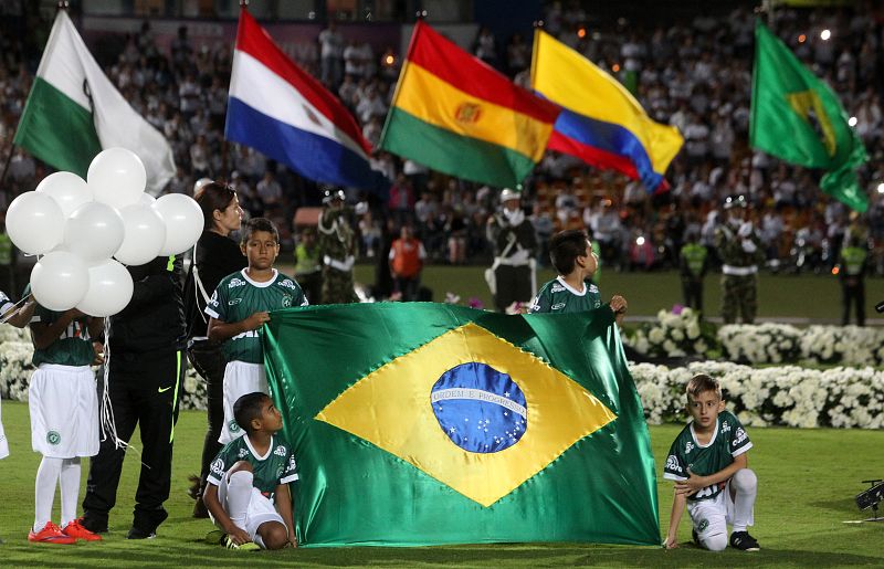 Un grupo de niños sostienen la bandera de Brasil durante el homenaje al equipo de fútbol Chapecoense.