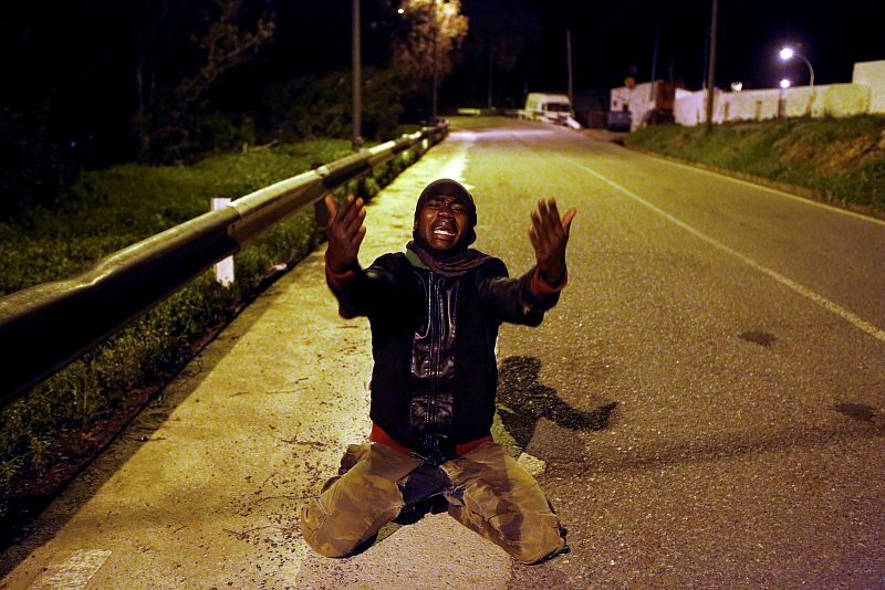 Un hombre gesticula arrodillado en la carretera después de cruzar la valla fronteriza entre Marruecos y España en Ceuta