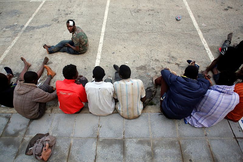 Un grupo de inmigrantes africanos descansan en el suelo tras haber saltado la valla fronteriza en Ceuta.