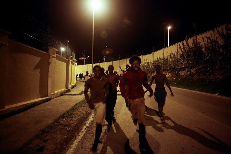 Unos jóvenes africanos corren por la carretera después de saltar la valla fronteriza en Ceuta