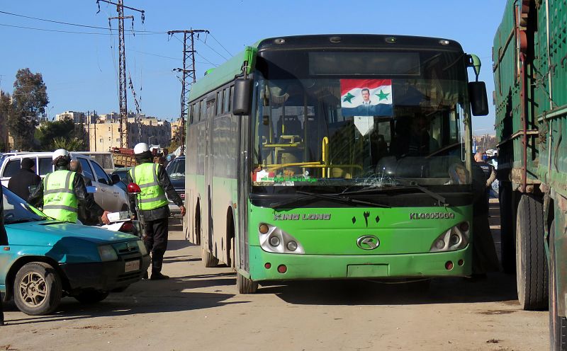 Un autobús de evacuación con la fotografía del presidente sirio Bachar al Asad.